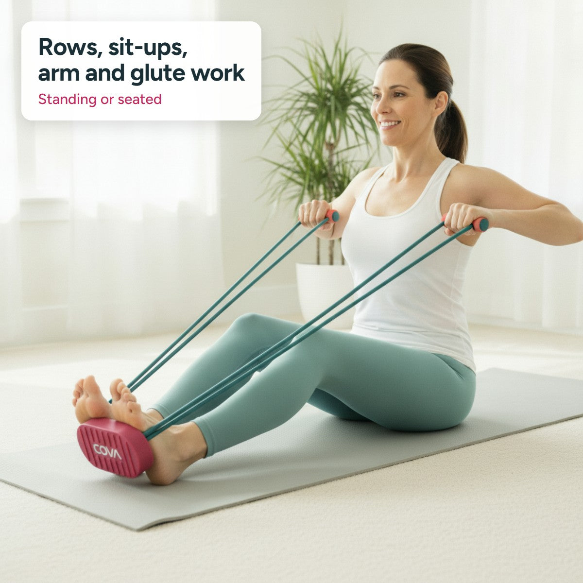 Woman doing a seated row with the COVA pedal band on a mat at home