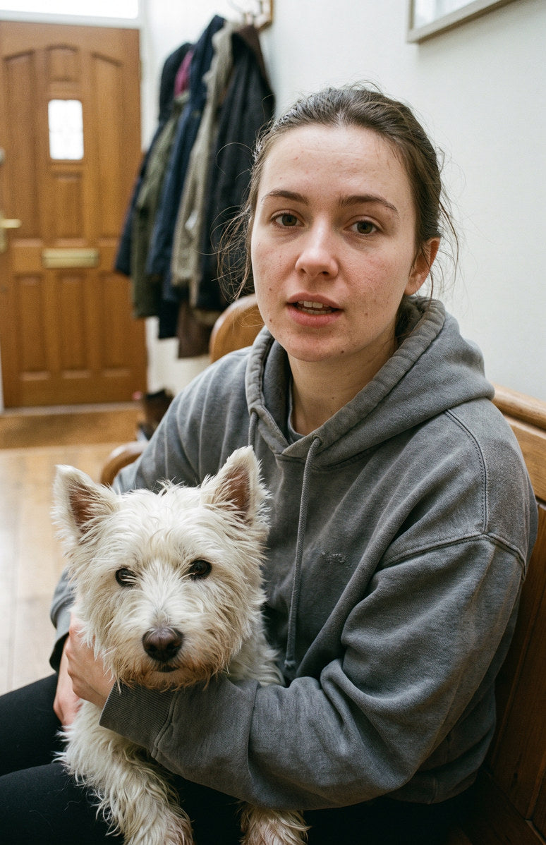 An owner on a hallway bench with her west highland white terrier