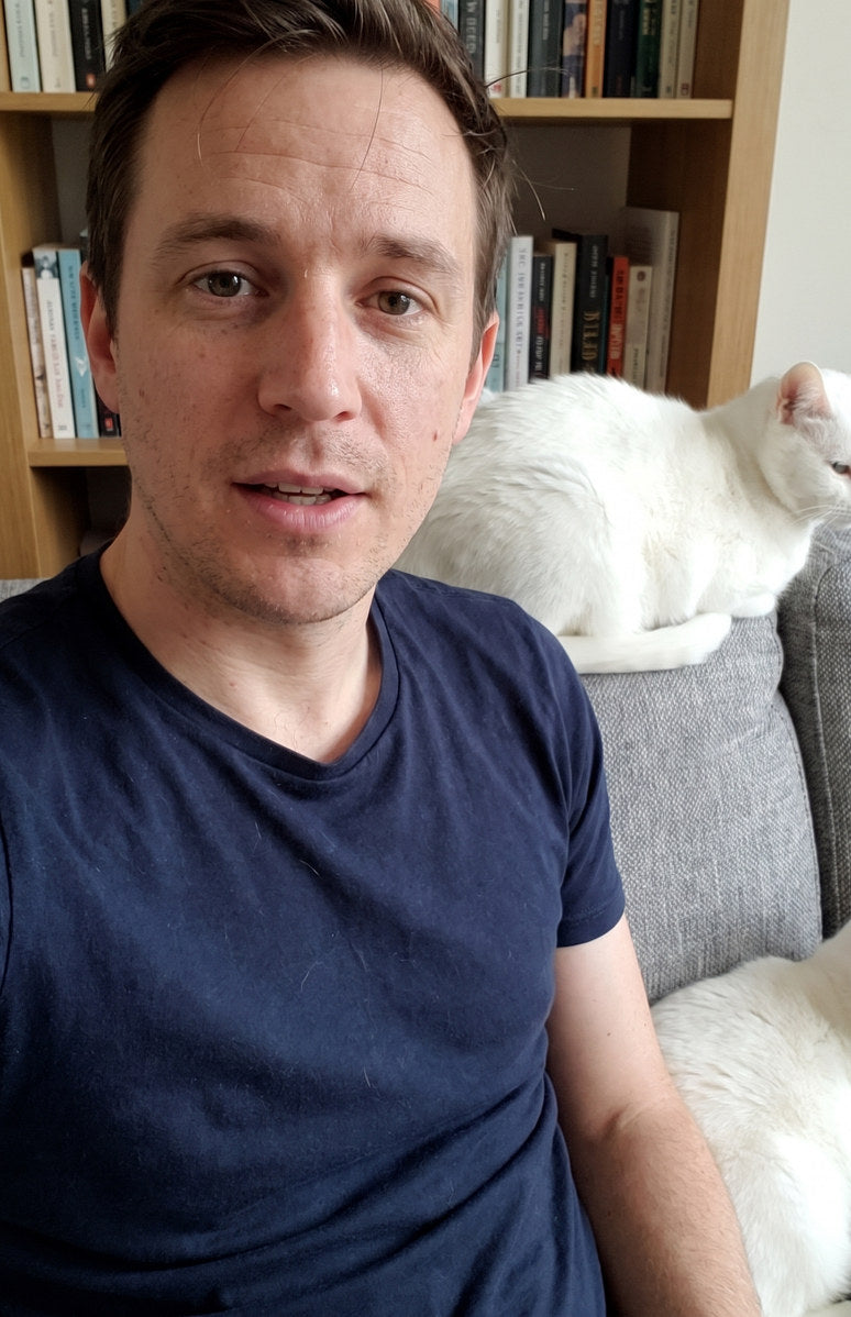 An owner on a sofa with his two white cats